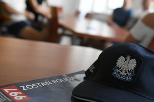 czapka policyjna , pod nią gazeta 997 z napisem zostań policjantem