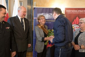 Zdjęcie kolorowe. Zdjęcie przedstawia wyróżnioną w konkursie Aktywny senior Renate Böhm ze Stowarzyszenia na rzecz odnowy i rozwoju lokalnego sołectwa Rudno, oraz wręczających wyróżnienie w tym I Zastępca Komendanta Wojewódzkiego Policji w Katowicach