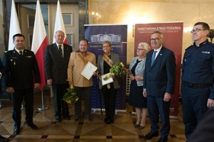 Zdjęcie kolorowe. Na zdjęciu widać od lewej nadbryg. Jacek Kleszczewski, Komendant Wojewódzki Państwowej Straży Pożarnej w Katowicach, wicewojewoda śląski Jan Chrząszcz, laureat konkursu Aktywny Senior Marek Wacław Judycki z Rudy Śląskiej, laureatka konkursu Aktywny Senior,  Renata Böhm ze Stowarzyszenia na rzecz odnowy i rozwoju lokalnego sołectwa Rudno,  poseł na Sejm RP Maria Nowak, Stanisław Szwed - Sekretarz Stanu w Ministerstwie Rodziny, Pracy i Polityki Społecznej, insp. Roman Rabsztyn, I Zastępca Komendanta Wojewódzkiego Policji w Katowicach.