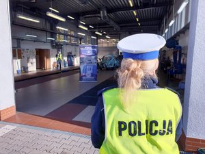 Na zdjęciu policjantka w mundurze stająca przed wjazdem do stacji diagnostycznej.