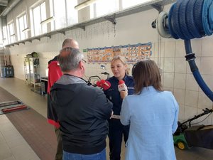 Na zdjęciu policjantka Wydziału Ruchu Drogowego KWP Katowice udziela wywiadu trzem dziennikarzom radiowym trzymającym w rękach mikrofony.
