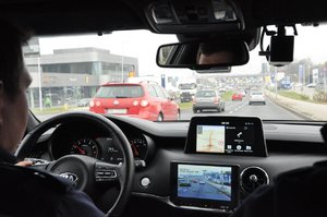 zdjęcie kolorowe: policjanci z grupy speed podczas wykonywania czynności na  drodze, widok z wnętrza pojazdu.