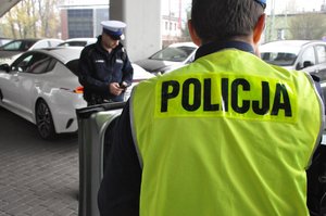 zdjęcie kolorowe: policjanci z grupy speed podczas wykonywania czynności na  drodze. Widok zza pleców policjanta.