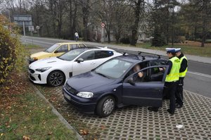 zdjęcie kolorowe: policjanci z grupy speed podczas wykonywania czynności na  drodze. Policjanci stoją przy sprawdzanym samochodzie, widok z wysokiej perspektywy.