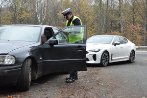 zdjęcie kolorowe: policjanci z grupy speed podczas wykonywania czynności na  drodze. Policjant stoi obok kontrolowanego pojazdu przy drzwi od strony kierowcy.