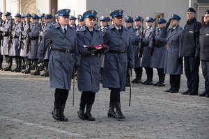 Zdjęcie kolorowe, przedstawiające policjantów niosących flagę.