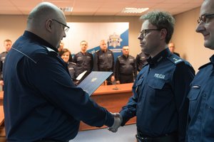 Zdjęcie kolorowe. Komendant Wojewódzki Policji w Katowicach nadinsp. dr Krzysztof Justyński wręcza policjantowi rozkaz o powierzeniu pełnienia obowiązków służbowych