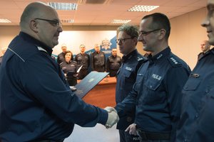 Zdjęcie kolorowe. Komendant Wojewódzki Policji w Katowicach nadinsp. dr Krzysztof Justyński wręcza policjantowi rozkaz o powierzeniu pełnienia obowiązków służbowych