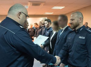 Zdjęcie kolorowe. Komendant Wojewódzki Policji w Katowicach nadinsp. dr Krzysztof Justyński wraz ze swoim Zastępcą gratuluje wyróżnionym policjantom