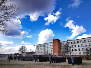 Policjanci na placu apelowym. W tle budynek OPP w Katowicach.