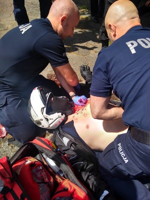 Policjanci udzielają pierwszej pomocy poszkodowanemu.
