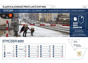 Pierwsza karta kalendarza z miesiącem styczeń. Fotografia przedstawia dorosłą kobietę przechodzącą z dzieckiem pod zamkniętym szlabanem przejazdu kolejowego. Z prawej strony karty widnieje napis: "Dzieci kopią dorosłych. Dzieci naśladują zachowania dorosłych. Dając taki przykład dziecku, narażasz je na niebezpieczeństwo."