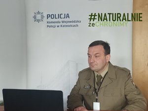 Jeden z prelegentów szkolenia. Ubrany w zielony mundur mężczyzna siedzi przed laptopem.