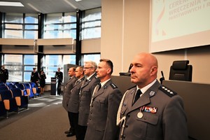 Zdjęcie przedstawia policjantów stojących w szeregu w trakcie uroczystości odznaczenia ich