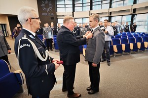 Zdjęcie przedstawia policjanta w trakcie odznaczenia go medalem przez Komendanta