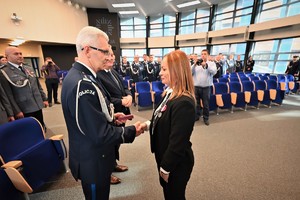 Zdjęcie przedstawia kobietę w trakcie odznaczenia jej medalem przez Komendanta