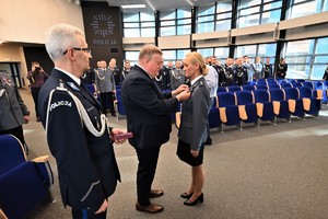 Zdjęcie przedstawia policjanta w trakcie odznaczenia go medalem przez Komendanta