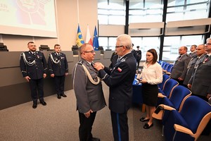 Zdjęcie przedstawia policjanta w trakcie odznaczenia go medalem przez Komendanta