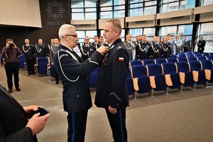 Zdjęcie przedstawia policjanta w trakcie odznaczenia go medalem przez Komendanta