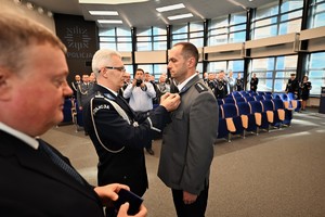 Zdjęcie przedstawia policjanta w trakcie odznaczenia go medalem przez Komendanta