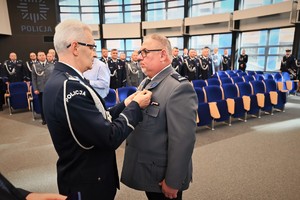 Zdjęcie przedstawia policjanta w trakcie odznaczenia go medalem przez Komendanta