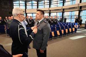 Zdjęcie przedstawia policjanta w trakcie odznaczenia go medalem przez Komendanta