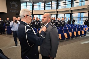 Zdjęcie przedstawia policjanta w trakcie odznaczenia go medalem przez Komendanta