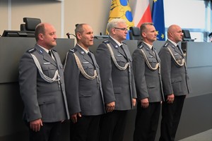 Zdjęcie przedstawia policjantów stojących w szeregu w trakcie uroczystości odznaczenia ich