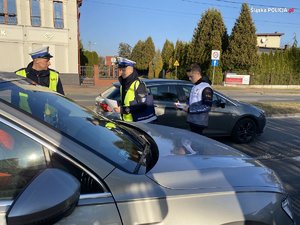 żużlowiec Mateusz Świdnicki z policjantami ruchu drogowego podczas rozmowy z kierowcą pojazdu osobowego