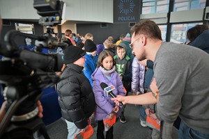 Zdjęcie. Uczestnik briefingu wypowiadający się przed mikrofonami dziennikarzy