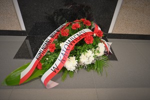 Zdjęcie. Widoczne kwiaty składane przed tablicą