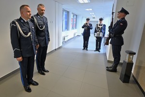 Zdjęcie. Umundurowani policjanci składają kwiaty przed tablicą