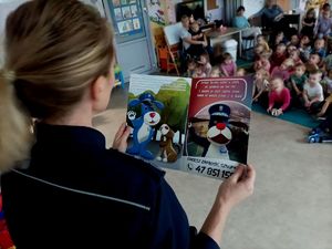 Zdjęcie przedstawiające policjantkę w trakcie czytania książki uczestnikom spotkania.