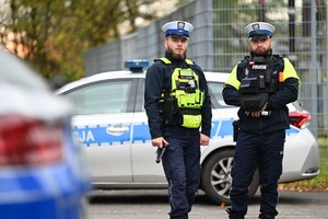 na zdjęciu policjanci ruchu drogowego stoją obok radiowozu