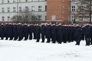 Policjanci składający ślubowanie stoją w rzędach i szeregach.