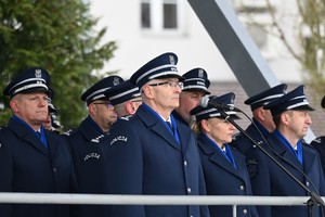 Przy mikrofonie stoi Komendant i kilku policjantów.