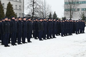 Policjanci składający ślubowanie stoją w rzędach i szeregach.
