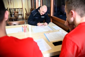 Policjant rejestruje się jako dawca, siedząc przy stole i wypełniając dokumenty.
