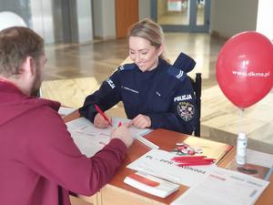 Zdjęcie. Osoba przy stanowisku DKMS z policjantem