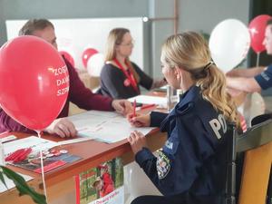 Zdjęcie. Osoba przy stanowisku DKMS z policjantem