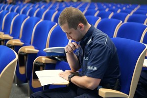 Na zdjęciu policjant podczas pisemnego testu z wiedzy ogólnej.