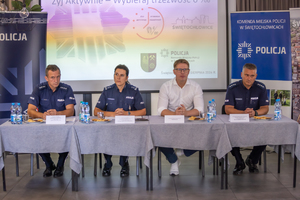 Zdjęcie kolorowe przedstawia siedzących za stołem policjantów prowadzących briefing wraz z Prezydentem Świętochłowic