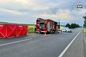 na zdjęciu czerwony parawan na jezdni, za nim wóz strażacki i radiowóz policyjny