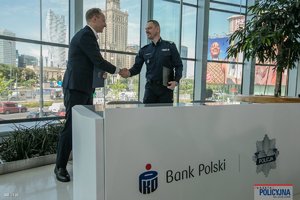 na zdjęciu komendant główny z przedstawicielem banku w trakcie uścisku dłoni za białym stołem