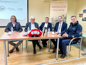 Na zdjęciu widocznych jest pięć osób siedzących przy stole. jedną z tych osób jest umundurowany funkcjonariusz Policji.