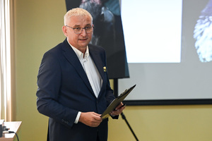 Na zdjęciu widoczny jest mężczyzna, który trzyma w rękach podkładkę do pisania z klipsem.
