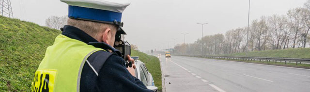 zdjęcie przedstawia umundurowanego policjanta dokonującego pomiaru prędkości