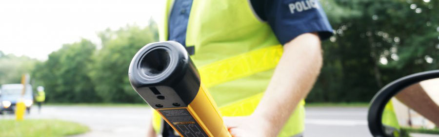 zdjęcie przedstawia rękę policjanta z alkotestem - zdjęcie zrobione z wnętrza pojazdu 