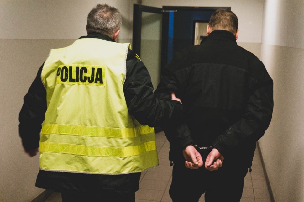 Policjant prowadzi zatrzymanego 