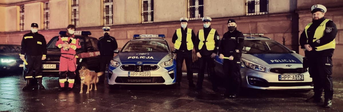policjanci, strażacy stoją przy pojazdach służbowych